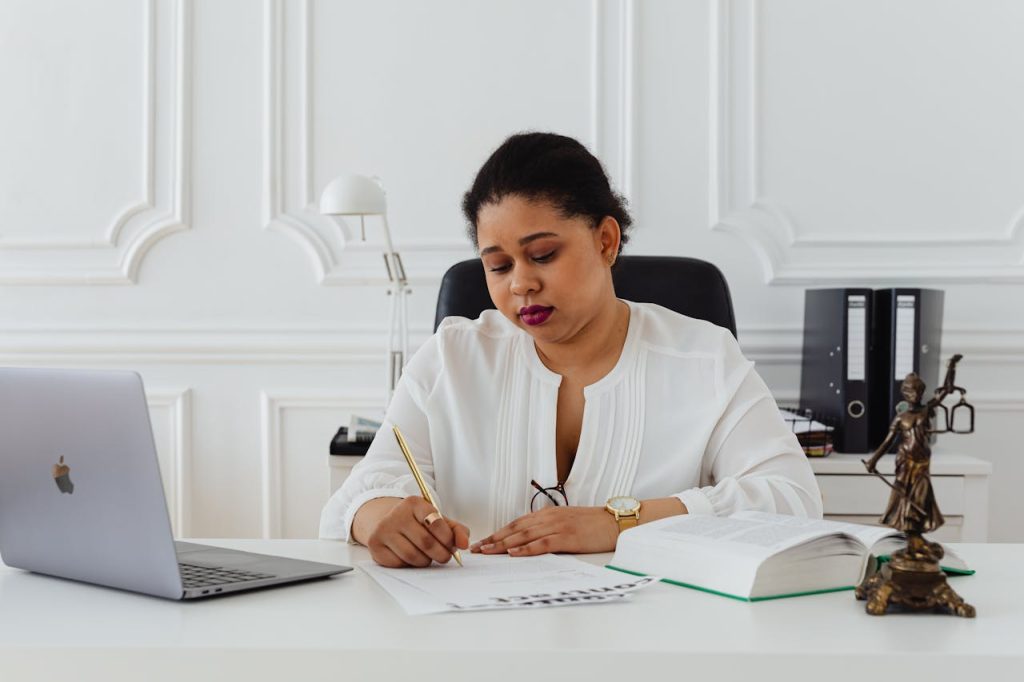 woman-at-her-office-signing-a-contract-7875843 African American woman lawyer signing documents at a desk, symbolizing professionalism.